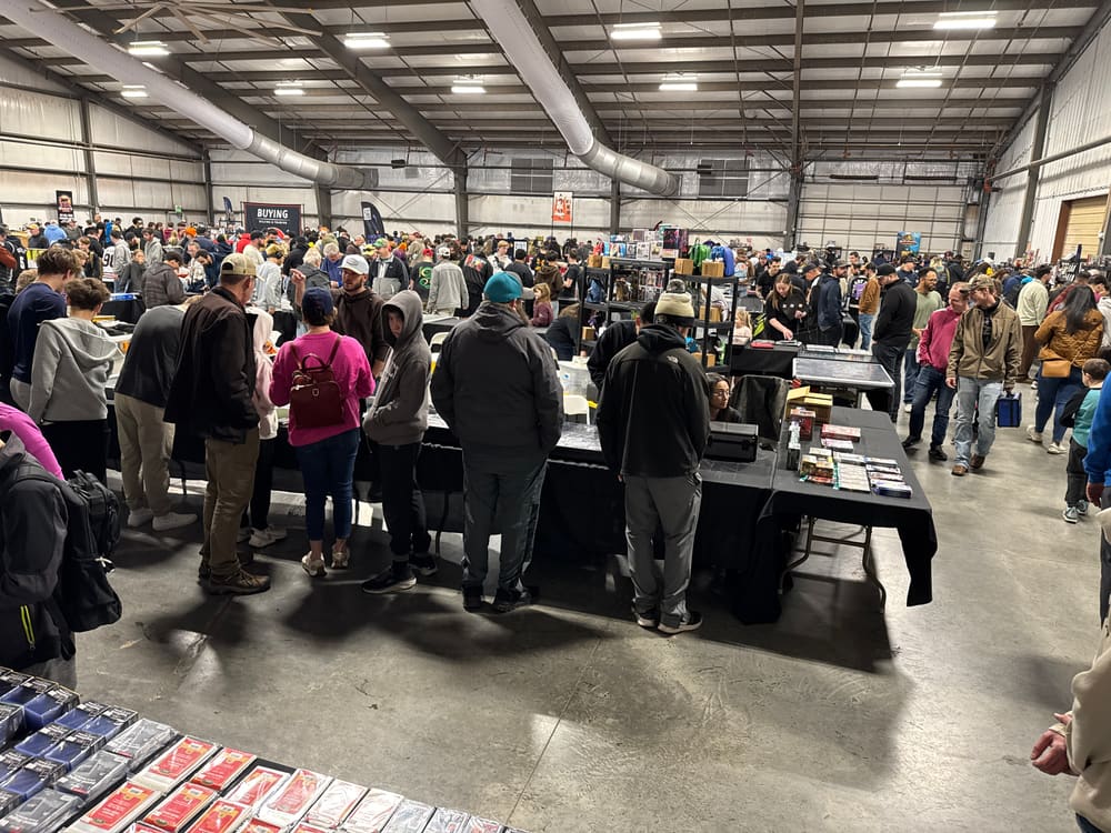 Kids digging through boxes of cards at a vendor table alongside their parents
